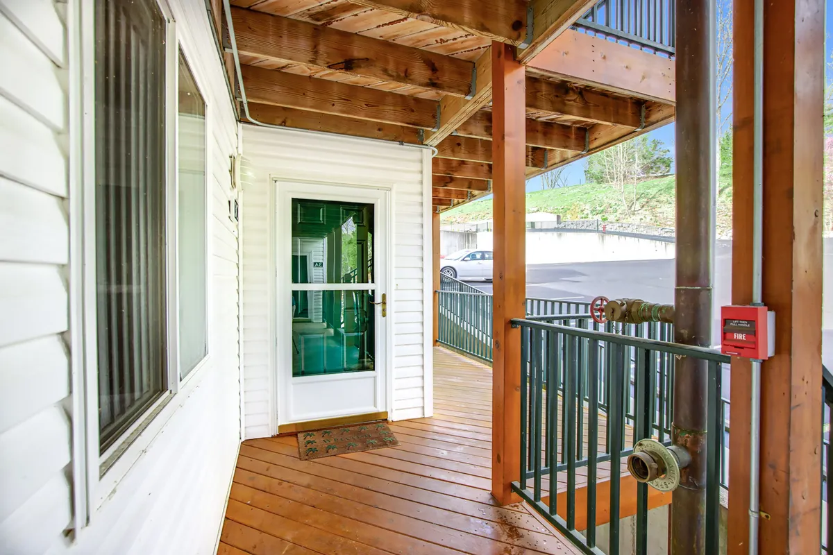 This image shows the inviting front door and deck railing of the condo, with wooden flooring leading guests into the home. The outdoor setting hints at warm weather and provides a sense of arrival, perfect for welcoming groups and setting the stage for outdoor entertaining.
