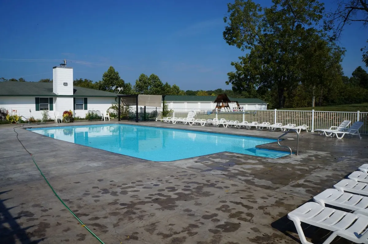 A tranquil outdoor swimming pool surrounded by comfortable lounge chairs and lush greenery. The setting features guests casually sunbathing, socializing around the pool, and enjoying the relaxed, adult-focused ambiance. The area feels private and secure, ideal for restful afternoons and sunset swims.