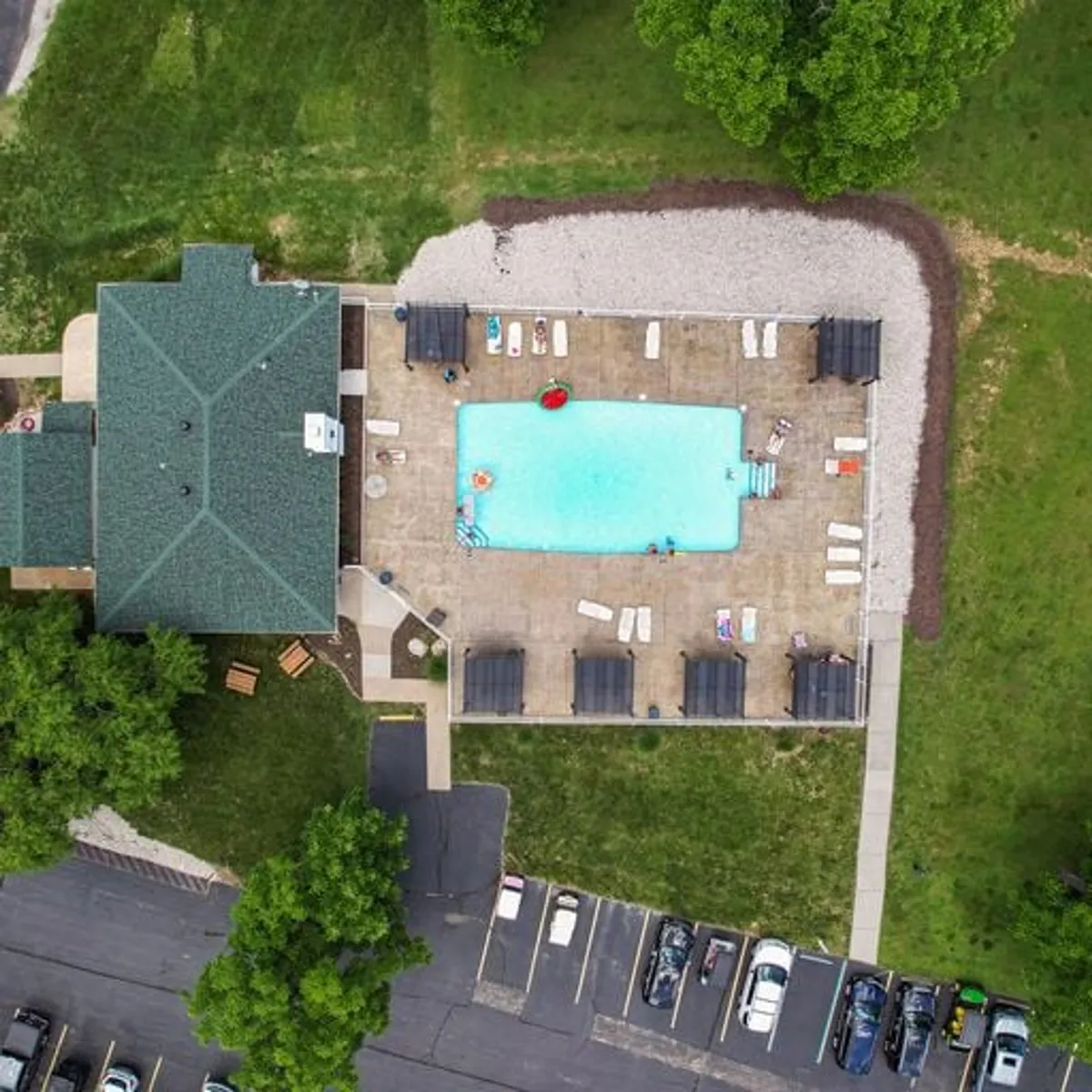 Expansive view of a sparkling pool with loungers and stylish poolside cabanas, set against a backdrop of green foliage. The image captures the leisurely vibe of guests relaxing by the water, basking in the sun, and enjoying peaceful moments in a sophisticated, well-maintained space.