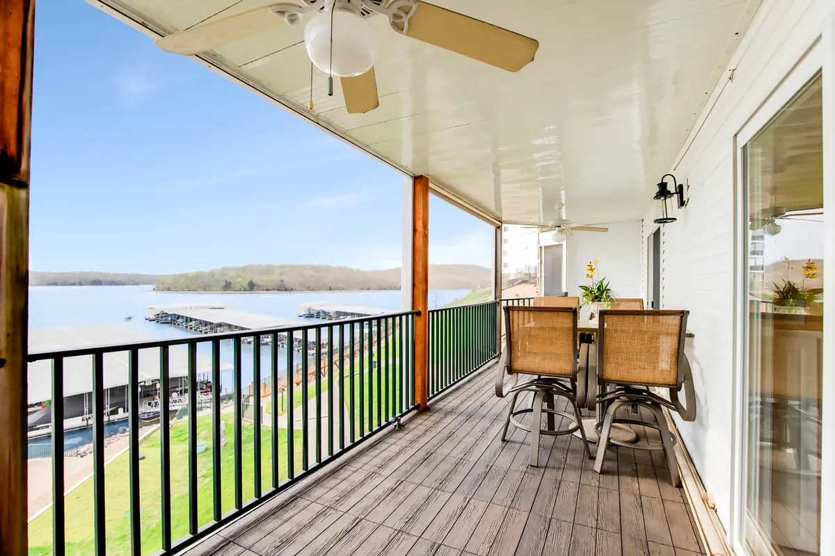 An outdoor deck set with a dining table and chairs, overlooking serene waterfront views with a dock area in the background. The setting is tranquil, perfect for enjoying meals outdoors while taking in the natural beauty and peaceful atmosphere.